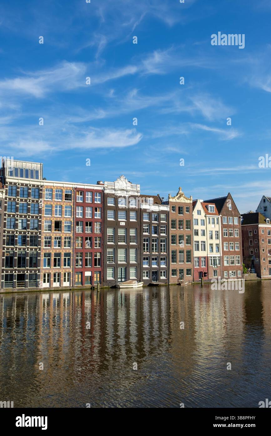 Les maisons de canal d'Amsterdam se reflètent dans l'eau par une journée ensoleillée, mettant en valeur l'architecture néerlandaise. Banque D'Images