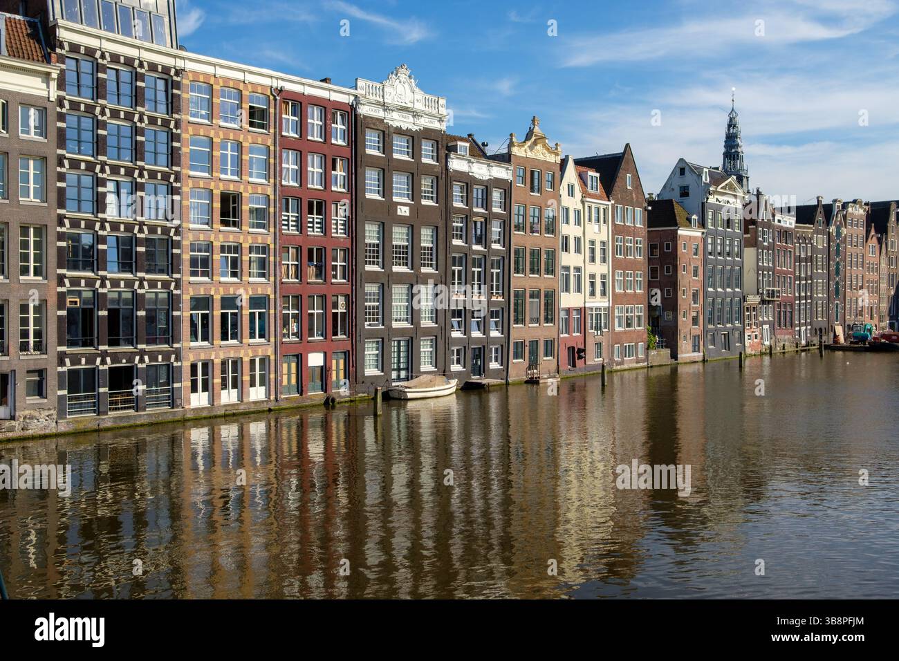 Les emblématiques maisons de canal d'Amsterdam bordent l'eau, reflétant leurs façades colorées par une journée ensoleillée. Banque D'Images