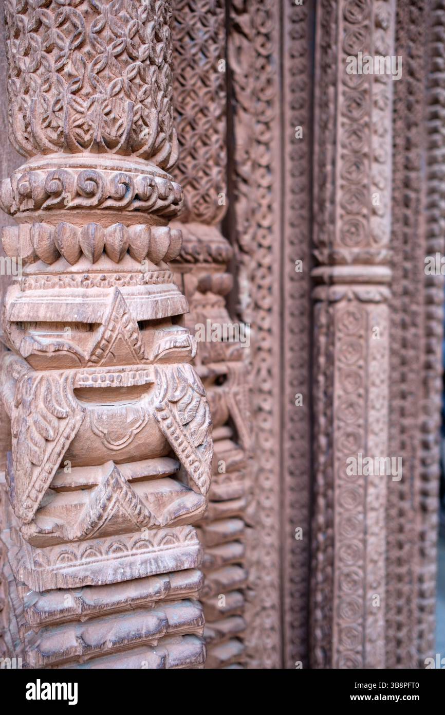 Des sculptures en bois complexes ornent une colonne de temple au Népal, mettant en valeur le riche patrimoine artistique de la région. Banque D'Images