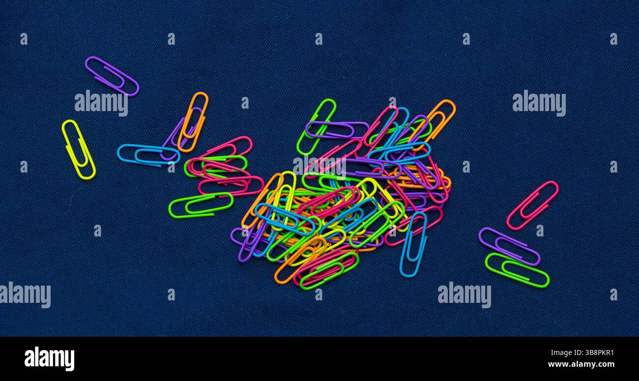 Grande pile de trombones en métal coloré sur fond sombre Banque D'Images