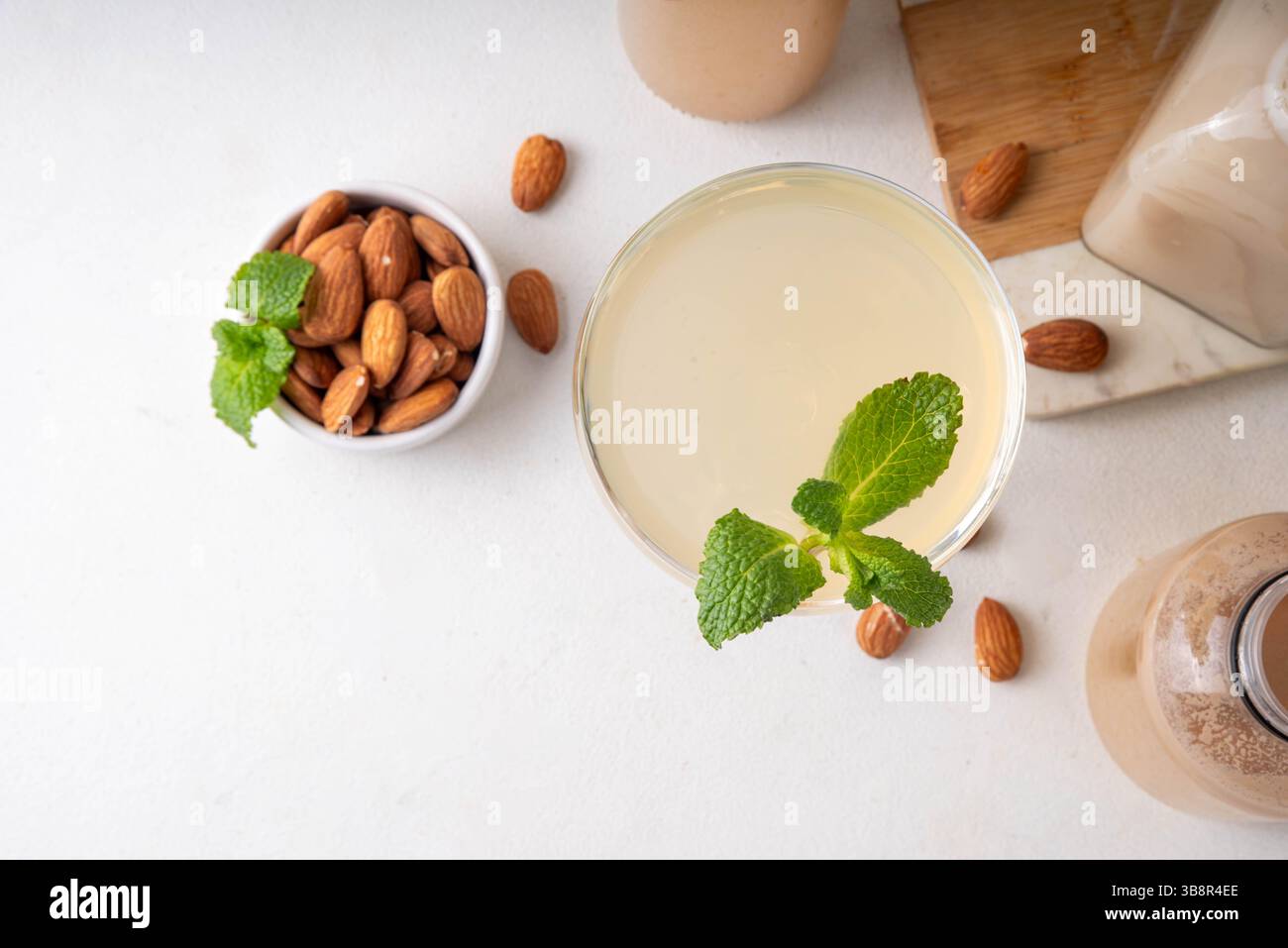 Cocktail d'orgeat au citron aigre-doux, recette de limonade à l'orgeat, un verre à martini avec boisson alcoolisée et bouteille de sirop d'orgeat d'amande Banque D'Images