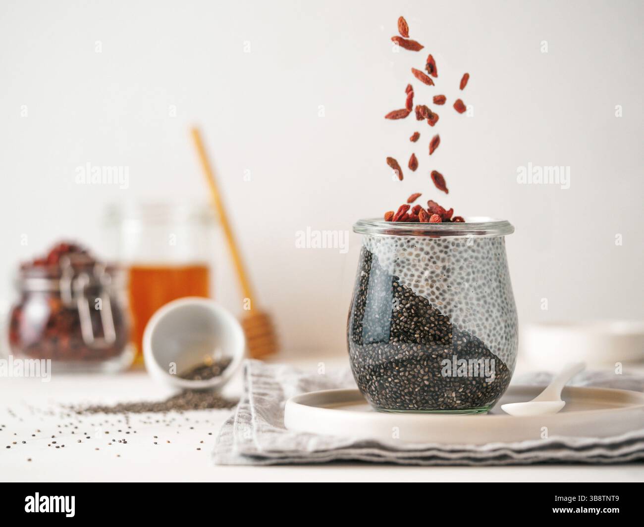 Petit-déjeuner sain concept et idée - deux couleurs chia pudding avec les matières premières organiques de goji. Bocal en verre avec du charbon noir et blanc lait vegan chia pu Banque D'Images