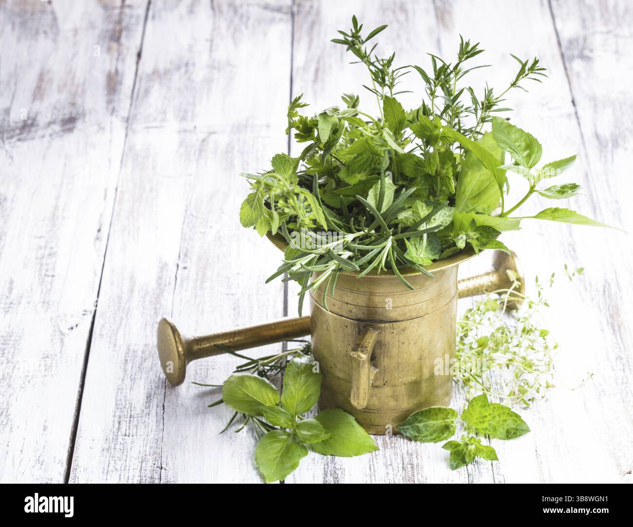 Des herbes fraîches dans le mortier de cuivre sur la table en bois miteux Banque D'Images
