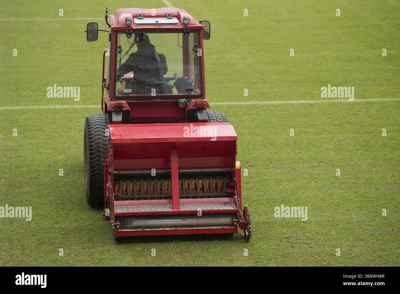 Un homme dans un tracteur avec un semoir à disques semant de l'herbe sur un terrain de football à Lubin, Pologne, Europe Banque D'Images