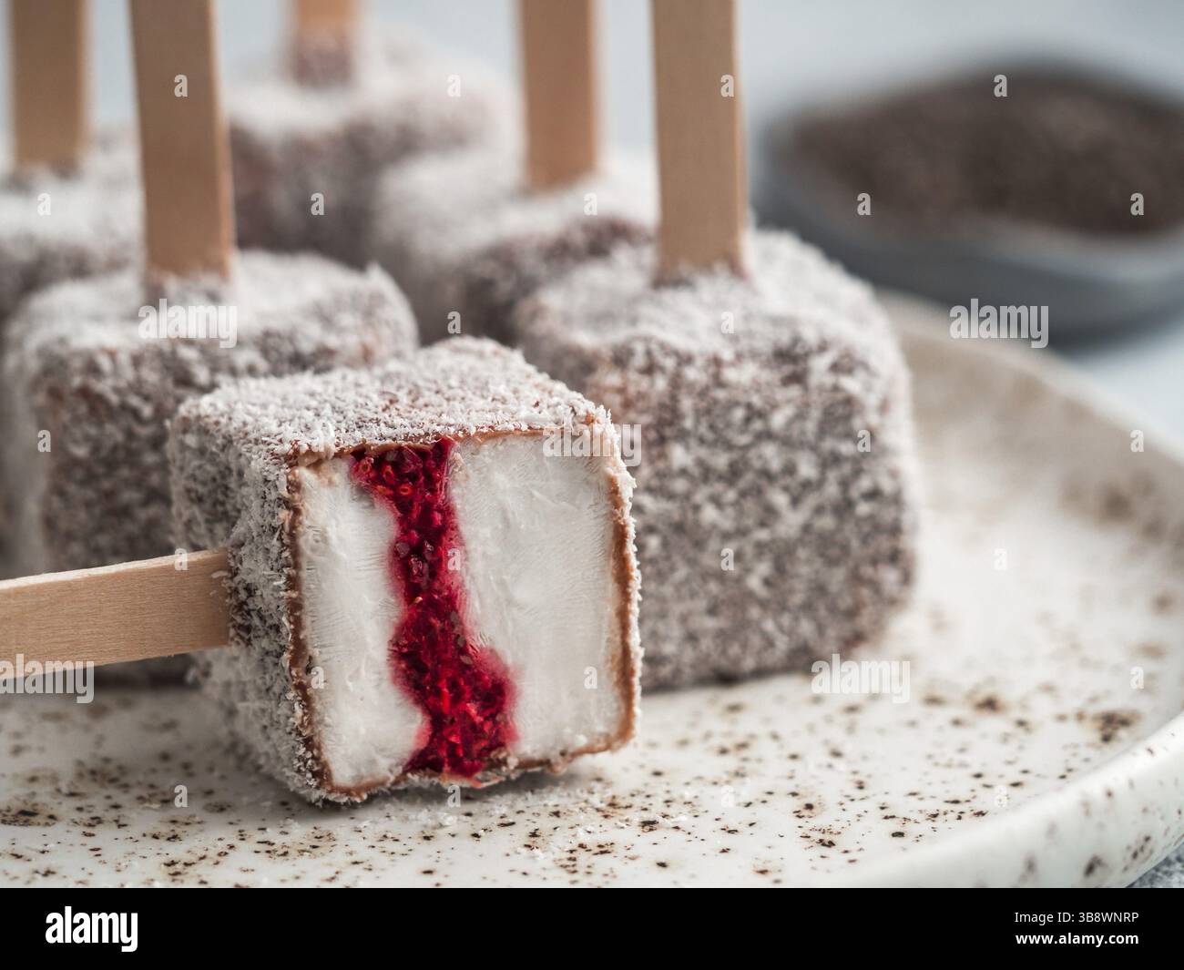 La crème glacée faite maison lamington raw pop sur fond clair. Australian dessert sucré avec lamington chia et framboises Confiture, Chocolat et cacao manteau. Banque D'Images