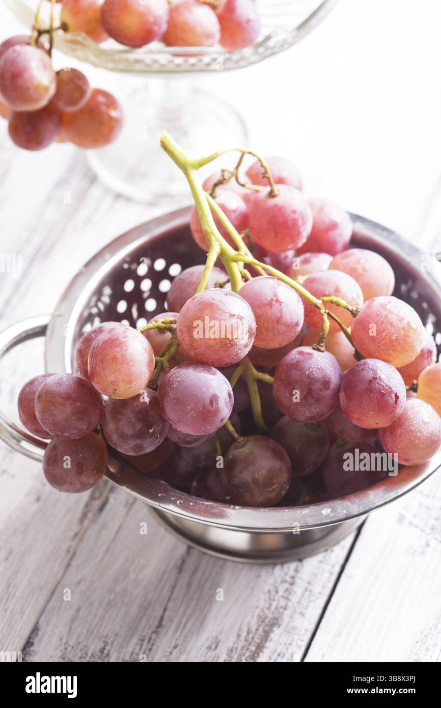 Gros raisins rouges dans une passoire sur le fond en bois Banque D'Images