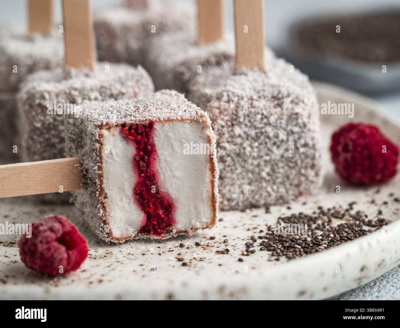 La crème glacée faite maison lamington raw pop sur fond clair. Australian dessert sucré avec lamington chia et framboises Confiture, Chocolat et cacao manteau. Banque D'Images