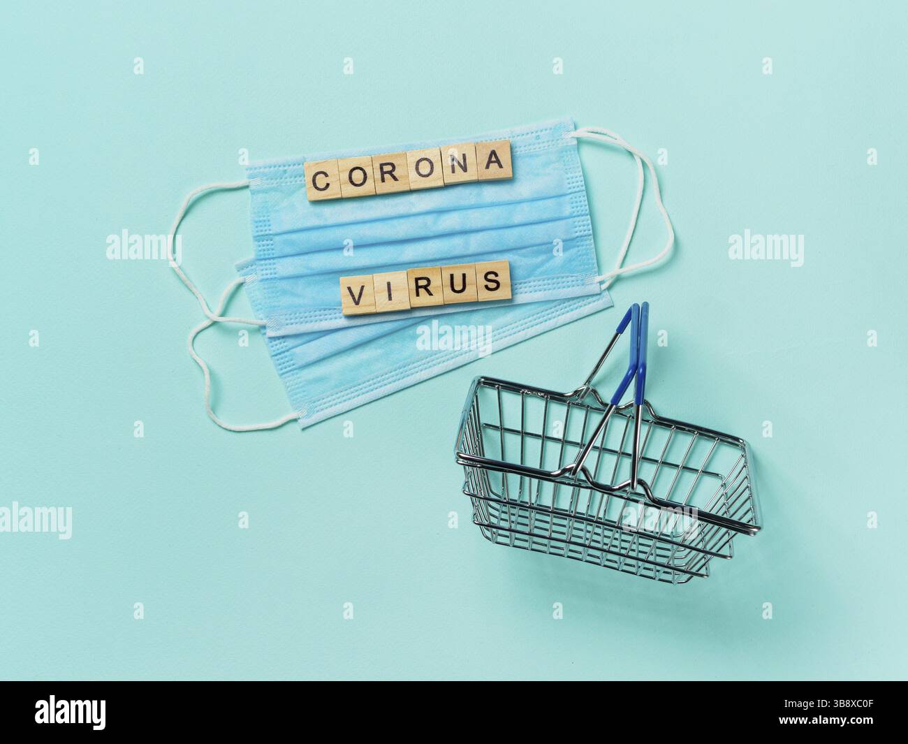Coronavirus et concept commercial. Masque respiratoire médical et chariot de shopping jouet sur fond bleu. Vue de dessus du concept de coronavirus. Espace de copie Banque D'Images