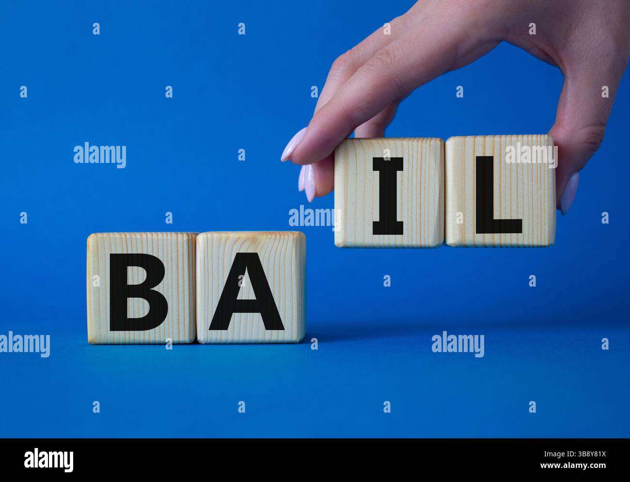 Symbole de béquille. Concept mot bail sur cubes en bois. Main d'homme d'affaires. Beau fond bleu. Business and bail concept. Copier l'espace. Banque D'Images