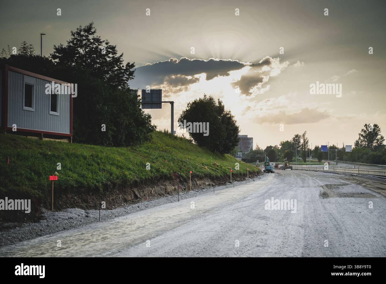 Les rayons du soleil brisent les nuages sur le site de construction de l'autoroute avec la base d'asphalte frais prête Banque D'Images