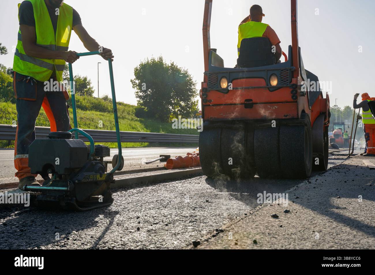 Plaque vibrante et rouleau compact compactant l'asphalte frais sur le chantier de construction d'autoroute Banque D'Images