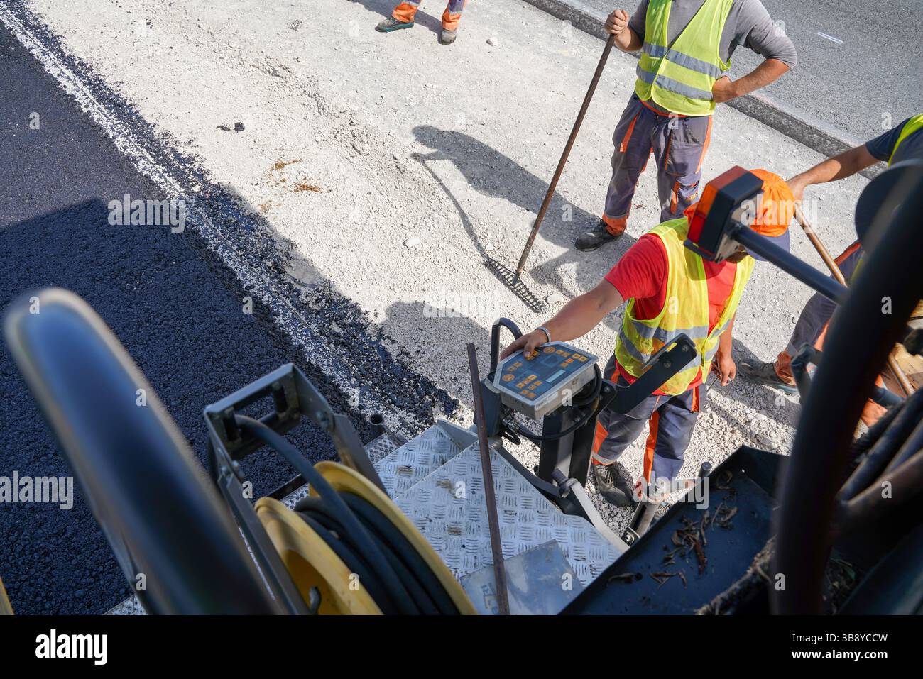 Ouvrier conduisant un finisseur sur un chantier de construction d'autoroute Banque D'Images