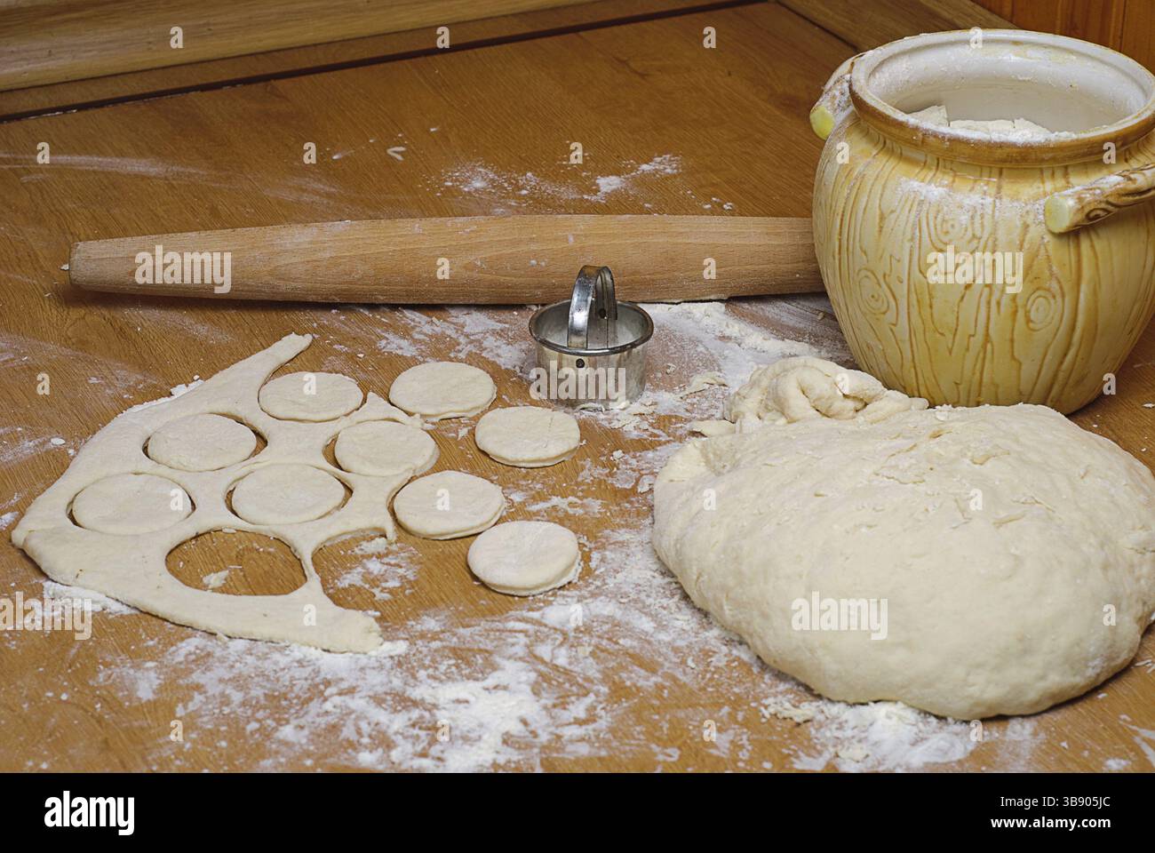 La farine dans la pâte et la capacité avec rouleau à pâtisserie sur la table en bois Banque D'Images