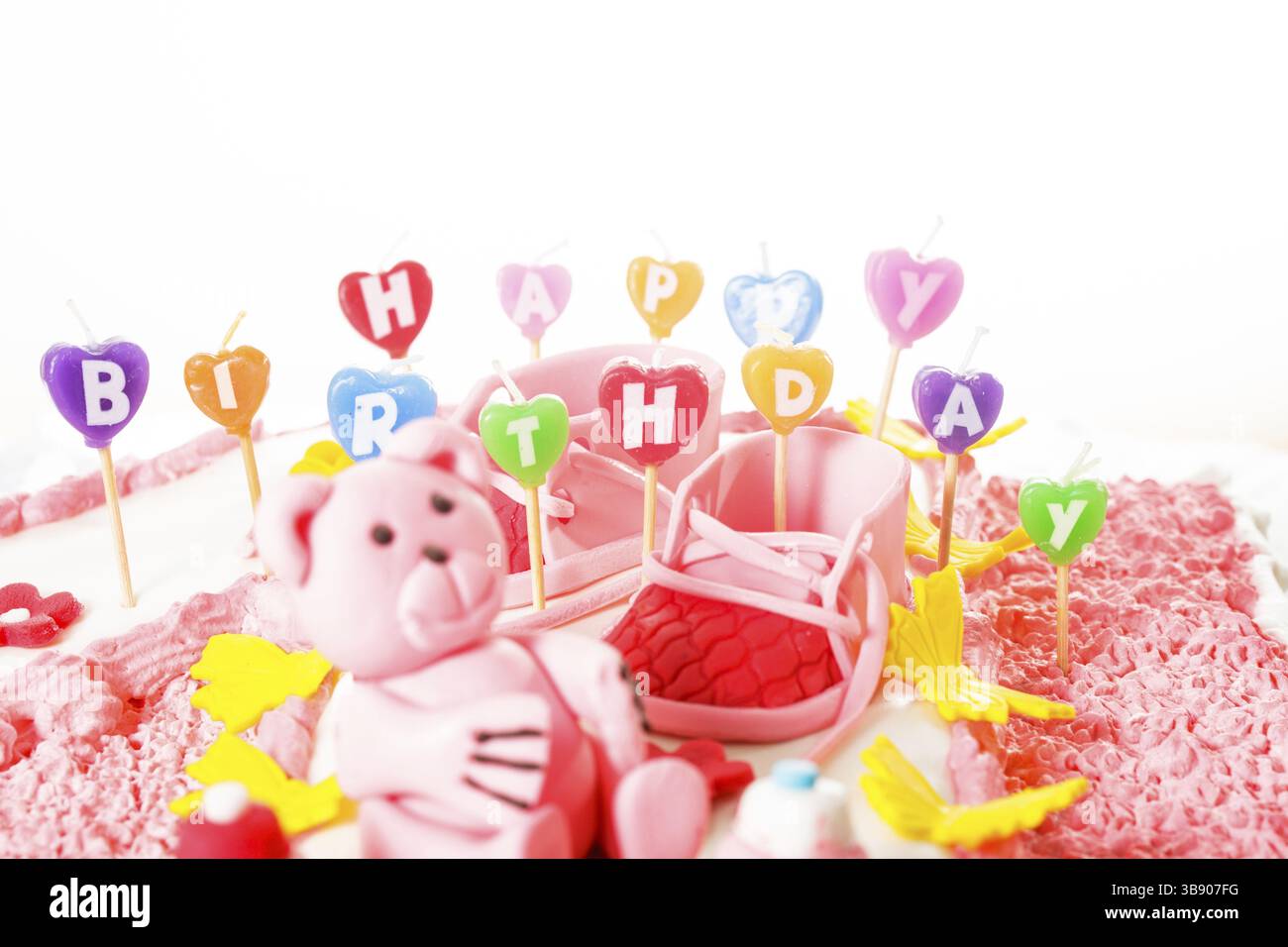 Un gâteau d'anniversaire rose pour enfants avec des bougies joyeux anniversaire Banque D'Images