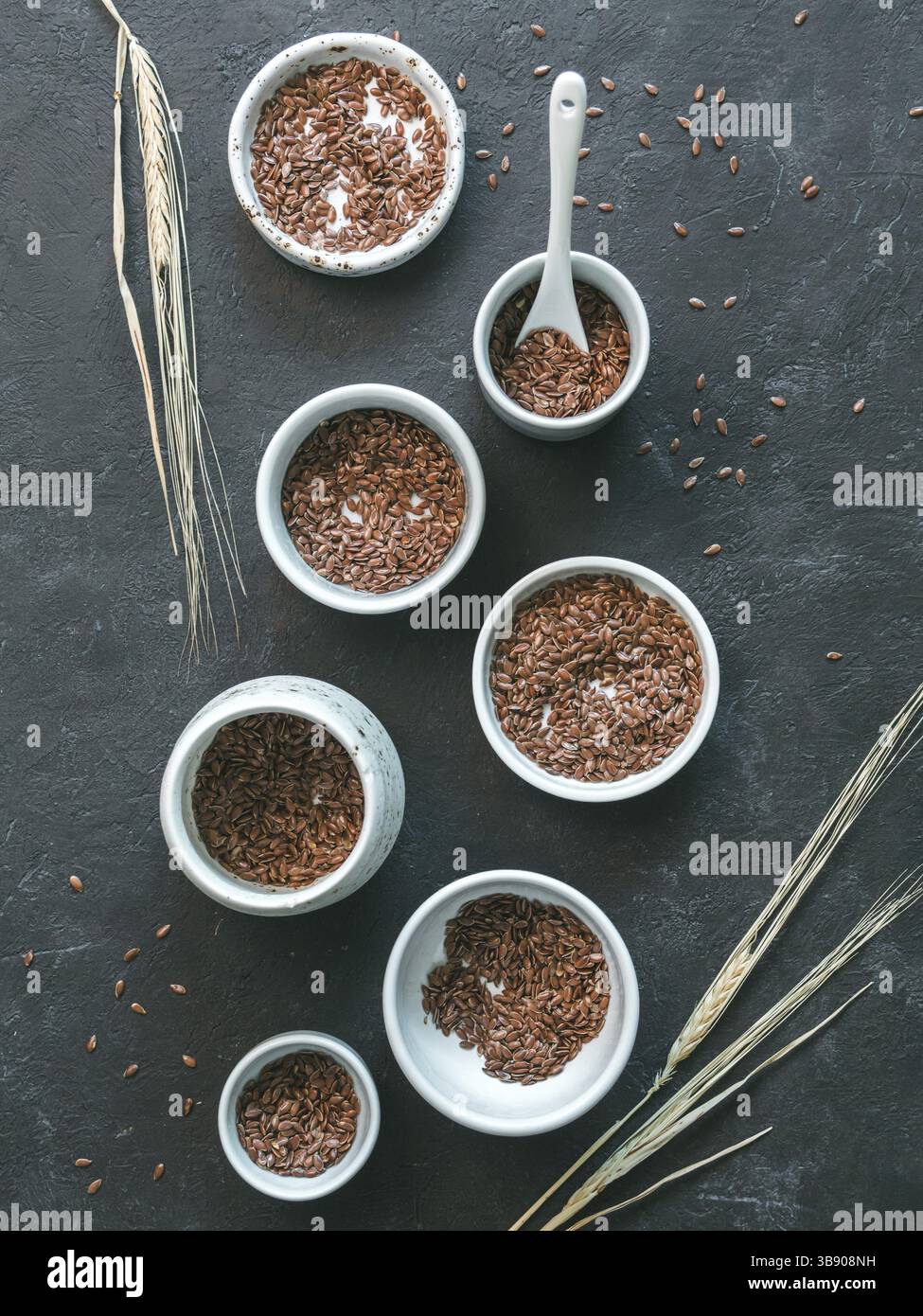 Graines de lin et épi de seigle sec sur fond sombre. Ensemble de petits bols avec graines de lin bio ou graines de lin. Les graines de lin sont riches en acides gras oméga-3. Vert Banque D'Images