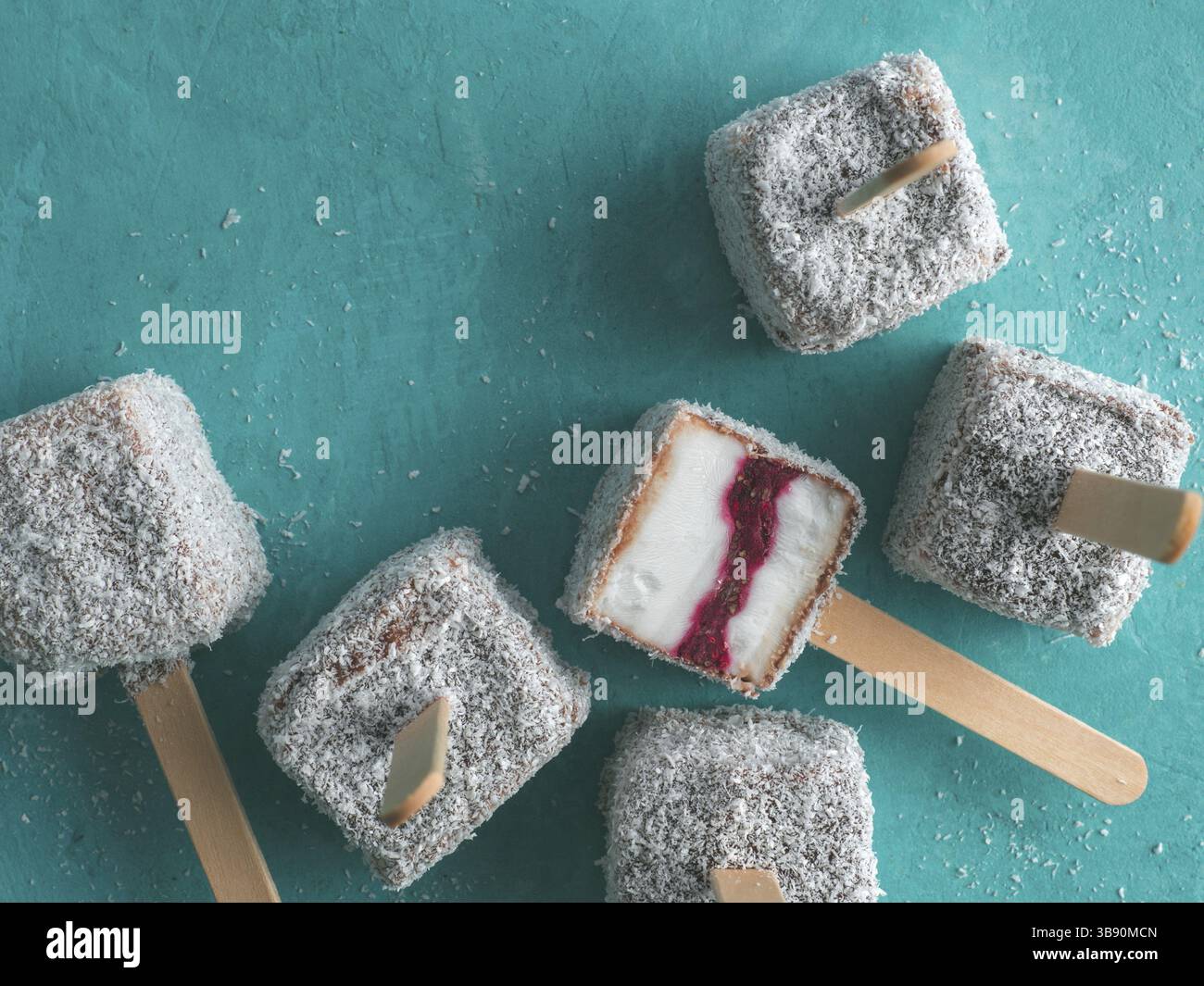 Crème glacée lamington crue maison pop sur fond bleu. Dessert australien sucré lamington avec confiture de chia et framboises, chocolat et manteau de cacao. Banque D'Images