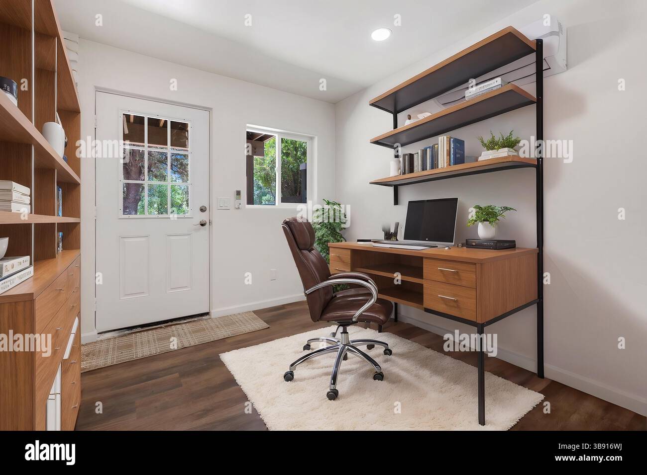 Un bureau à domicile confortable avec un bureau, une chaise, un ordinateur et des étagères Banque D'Images