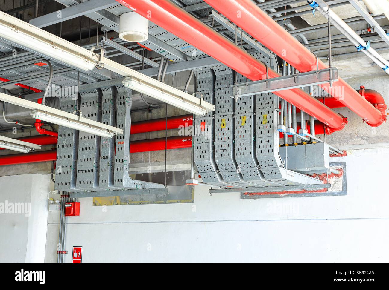 Canalisation électrique en acier, chemin de câble électrique sur le mur, acheminement de câble entre le panneau de distribution électrique avec l'équipement. Banque D'Images