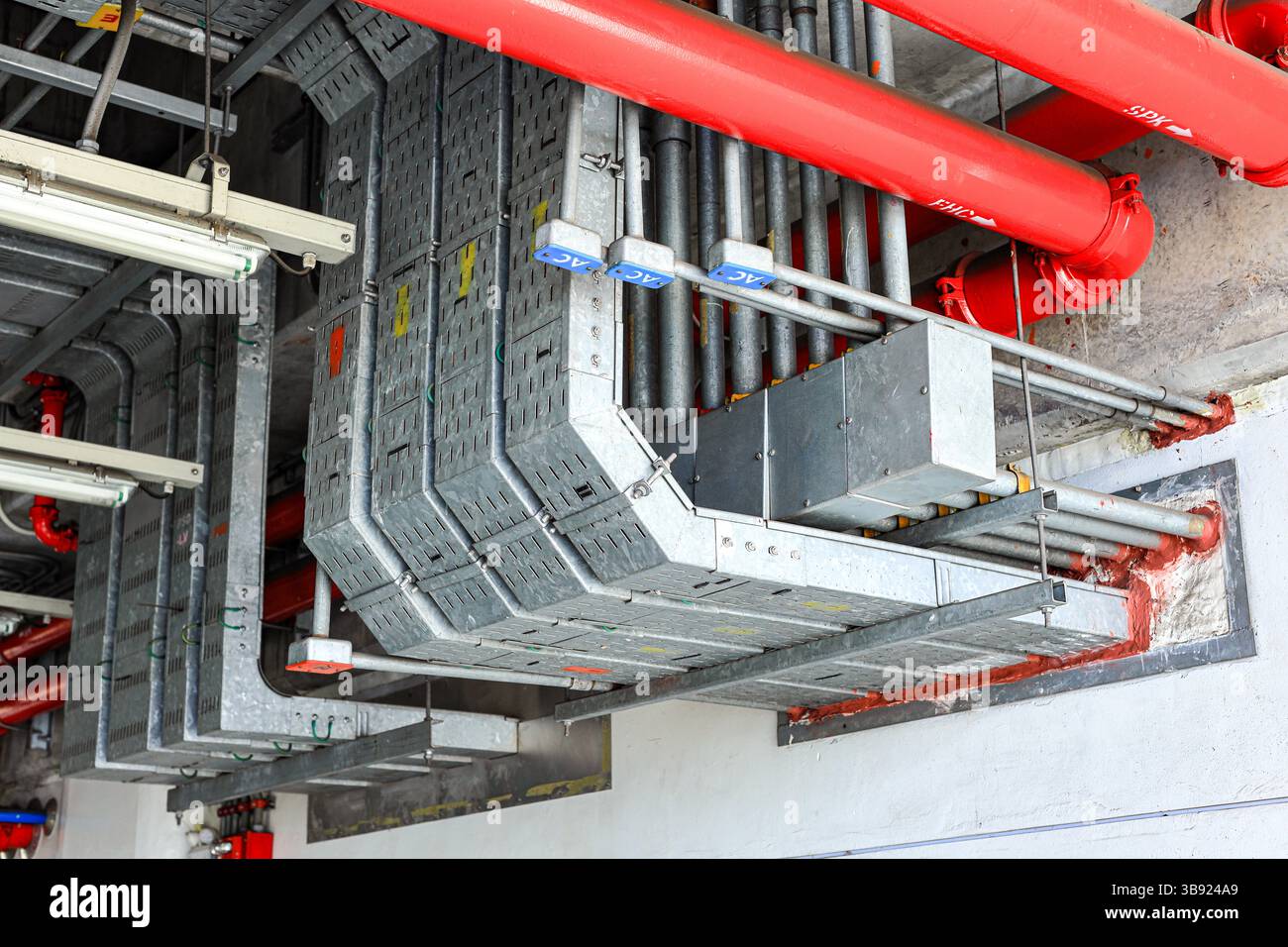 Canalisation électrique en acier, chemin de câble électrique sur le mur, acheminement de câble entre le panneau de distribution électrique avec l'équipement. Banque D'Images