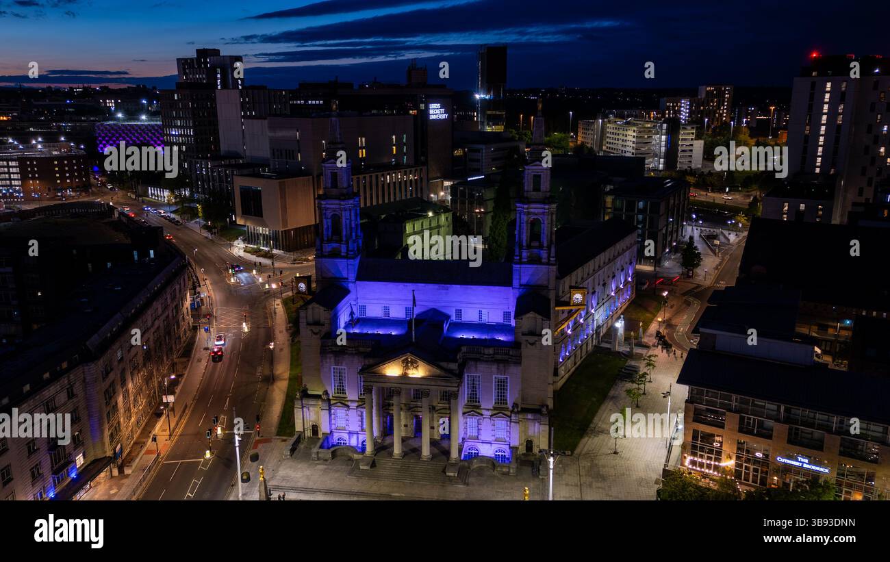 Vue aérienne de l'hôtel de ville de Leeds illuminé en violet au crépuscule, entouré par les feux de la ville et la circulation, mettant en valeur le paysage urbain dynamique de Leeds, Royaume-Uni Banque D'Images