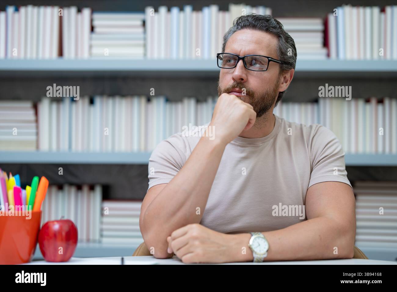 Portrait de l'enseignant avec livre dans la salle de classe de la bibliothèque. Beau professeur à la bibliothèque de l'université. Journée des enseignants. Cours de professeur. Professeur d'école Banque D'Images
