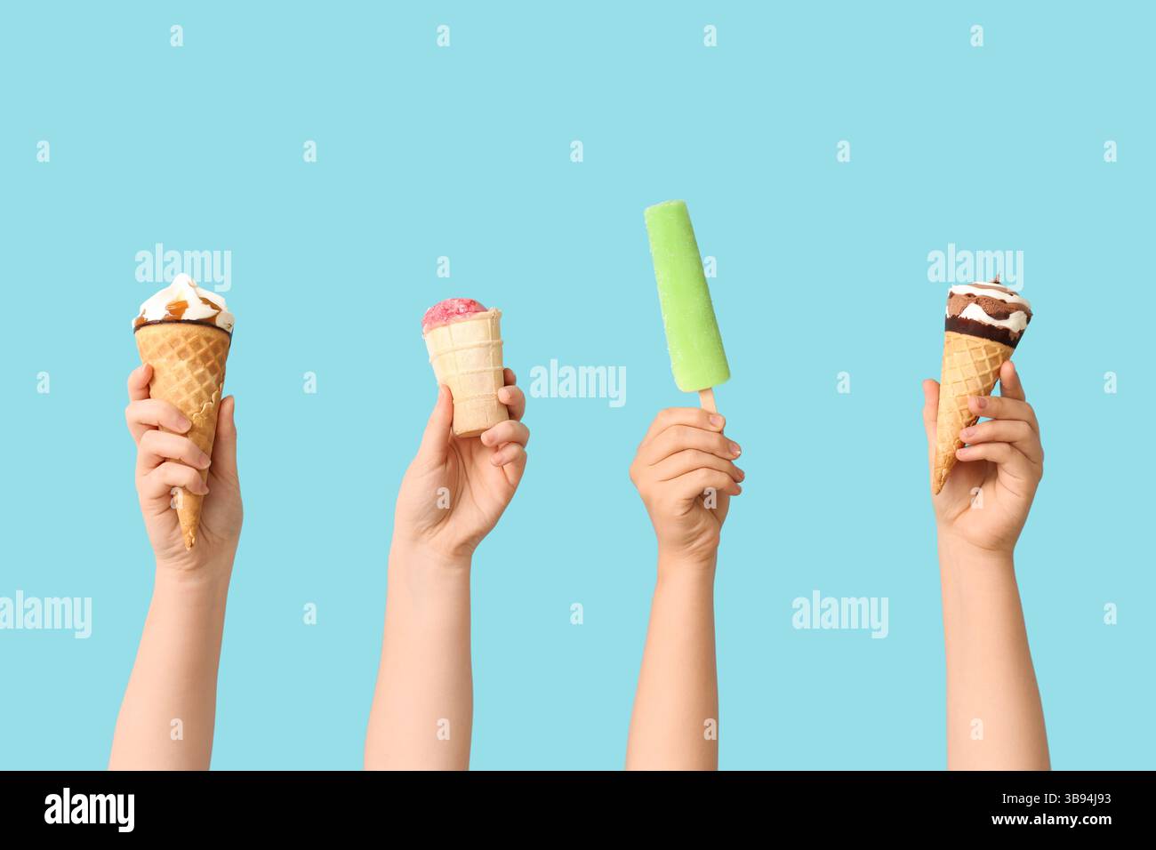 Mains féminines avec différentes glaces sucrées sur fond bleu Banque D'Images