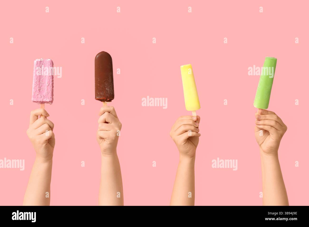 Mains féminines avec différentes glaces sucrées sur fond rose Banque D'Images