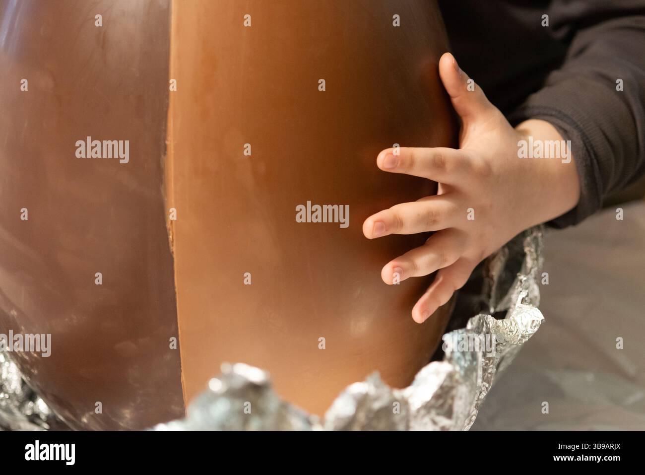 Garçon ouvrant un œuf de Pâques en chocolat géant Banque D'Images