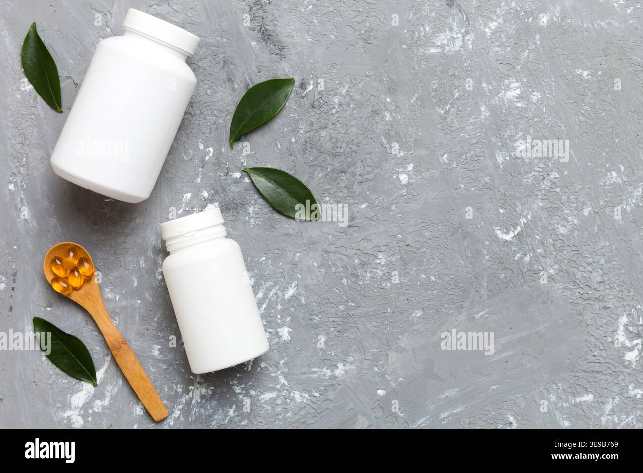 Les capsules Omega-3 se trouvent dans une bouteille blanche sur une table avec un fond de feuilles vertes. Comprimés d'huile de poisson. Additifs biologiquement actifs. omega 6, omega 9, vitam Banque D'Images