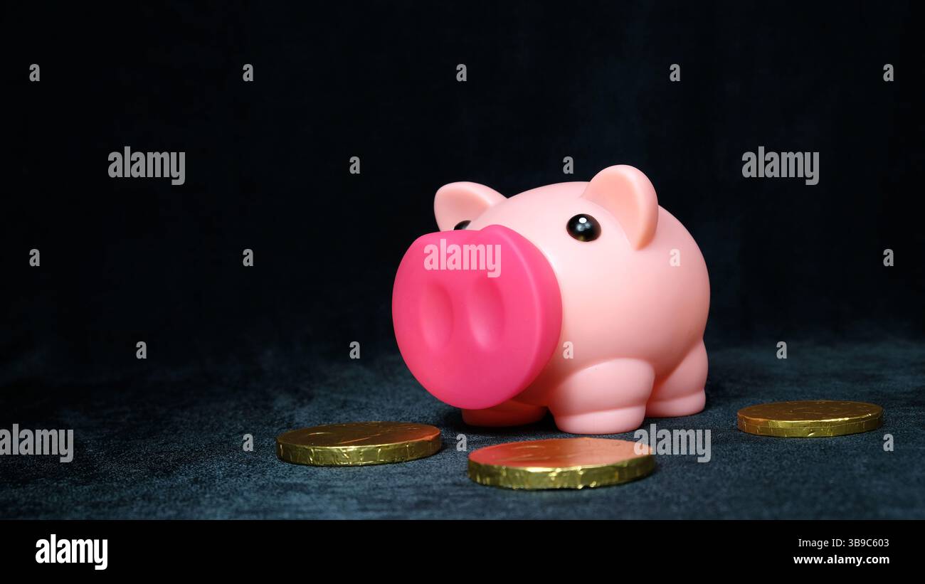 Tirelire rose avec des pièces en euros sur fond noir Banque D'Images