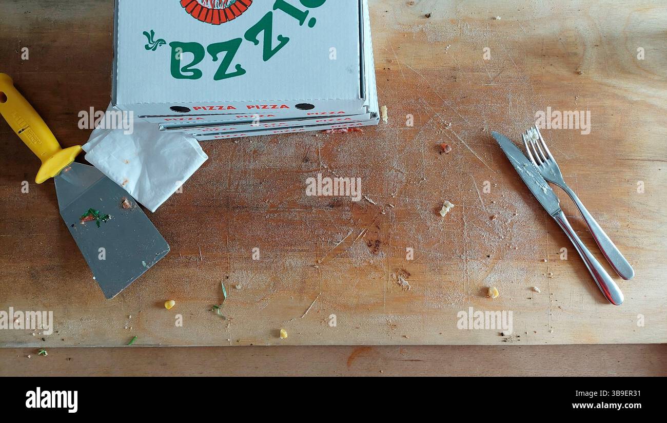 Planche de bois vide avec couteau et fourchette boîte à pizza après avoir mangé de la pizza Banque D'Images