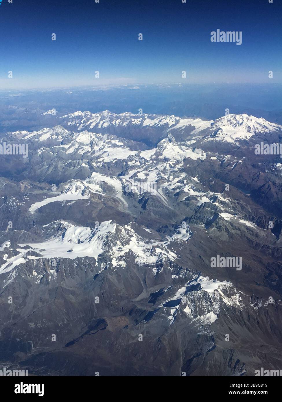 Vue aérienne réalisée depuis l'avion, survolant les Alpes européennes entre l'Italie et l'Autriche pendant l'été. Sommet des montagnes couvertes de neige. Banque D'Images