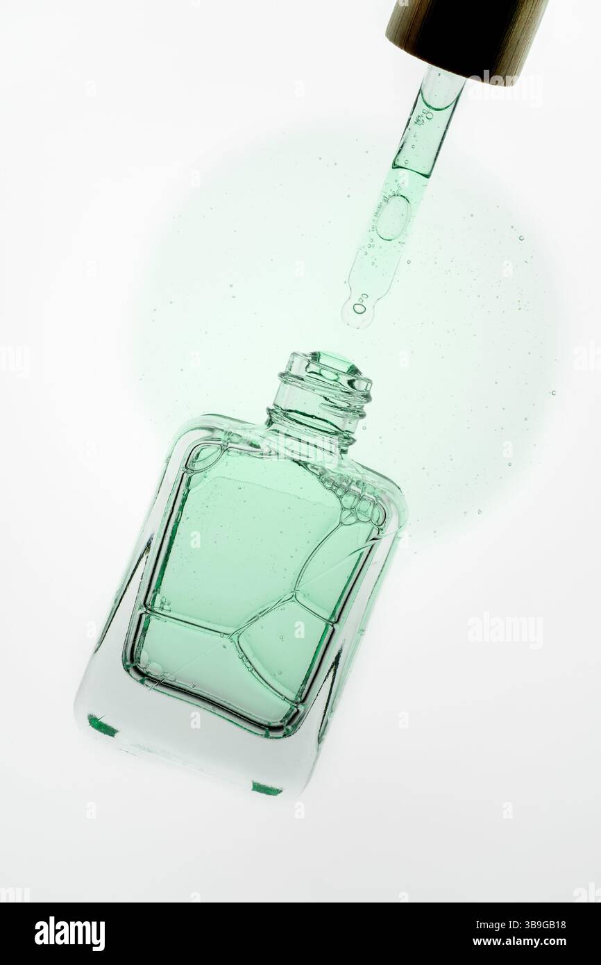 Gros plan d'un compte-gouttes libérant du liquide d'aloe vera dans une bouteille en verre. L'image met en évidence les produits de soins de la peau et cosmétiques, avec un accent sur les sérums et Banque D'Images