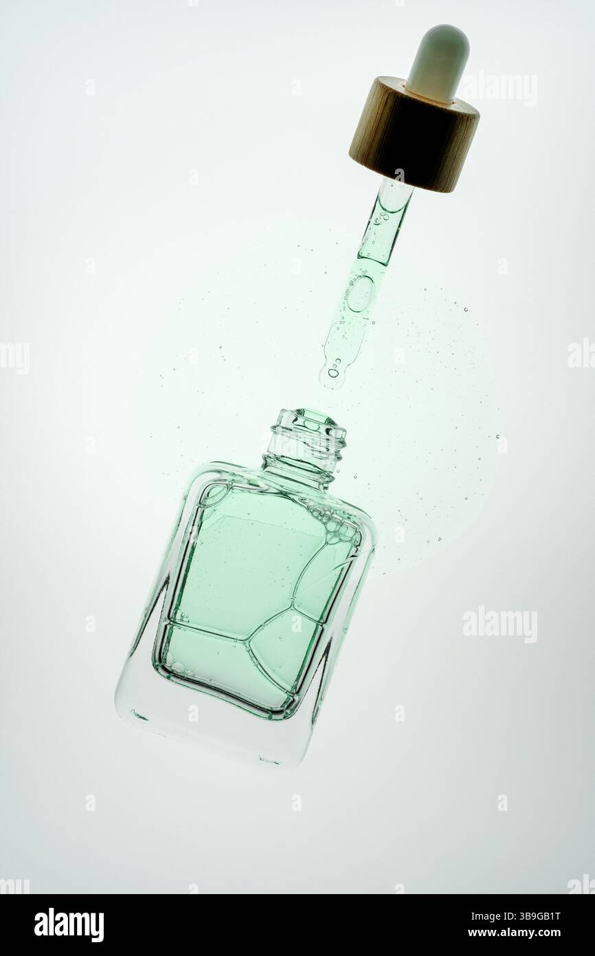 Gros plan d'un compte-gouttes libérant du liquide d'aloe vera dans une bouteille en verre. L'image met en évidence les produits de soins de la peau et cosmétiques, avec un accent sur les sérums et Banque D'Images