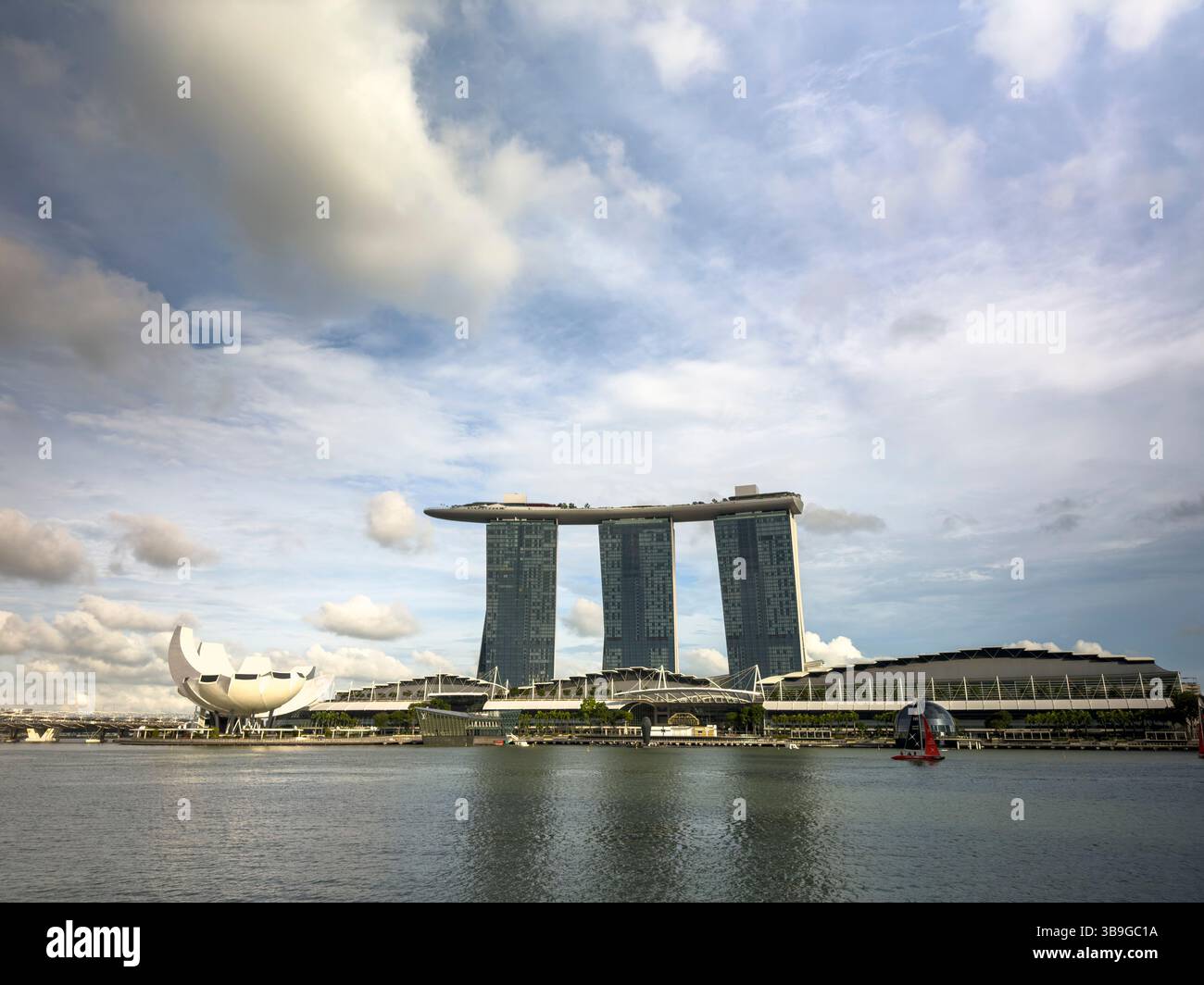 Vue captivante sur l'hôtel Marina Bay Sands et le musée ArtScience contre un ciel nuageux à Singapour, mettant en valeur l'architecture moderne et un bassin d'eau serein Banque D'Images