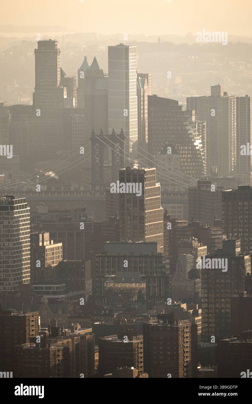 Vue d'en haut, cette image capture la ligne d'horizon dense et brumeuse de New York, avec une vue imprenable sur les gratte-ciel et l'architecture emblématique du pont fadi Banque D'Images