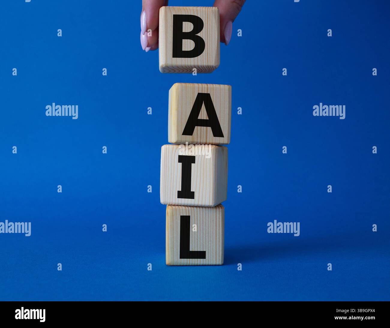Symbole de béquille. Concept mot bail sur cubes en bois. Main d'homme d'affaires. Beau fond bleu. Business and bail concept. Copier l'espace. Banque D'Images