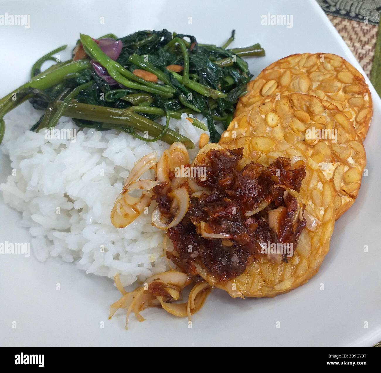 Tempe goreng avec tumis kangkung et sambal kecombrang, nourriture indonésienne servie sur un lit de riz blanc cuit à la vapeur sur une assiette blanche carrée Banque D'Images