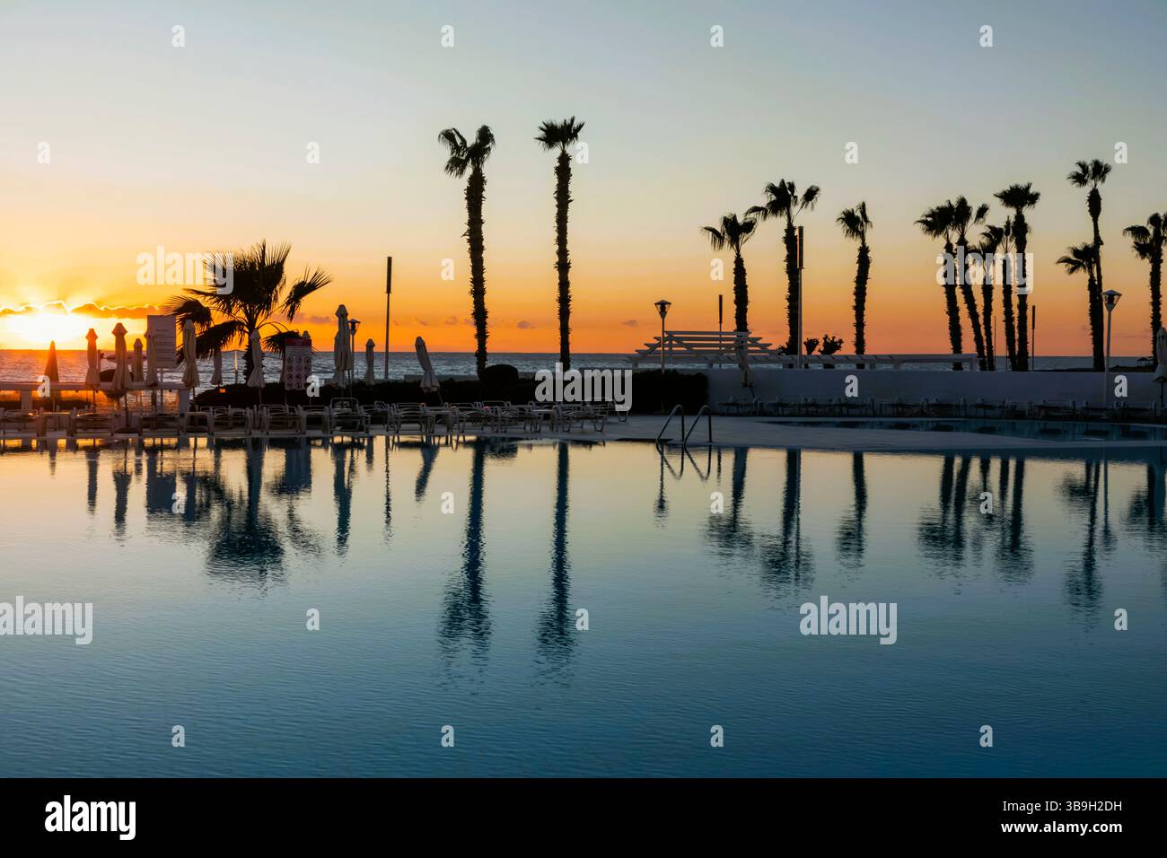 Chypre, Paphos, plage de Paphos avec des palmiers au coucher du soleil Banque D'Images