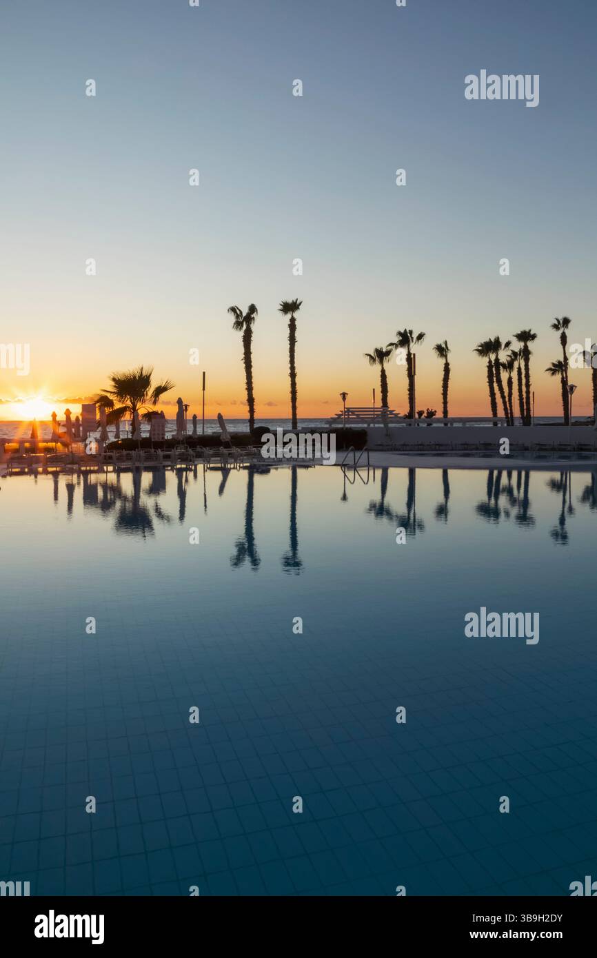 Chypre, Paphos, plage de Paphos avec des palmiers au coucher du soleil Banque D'Images