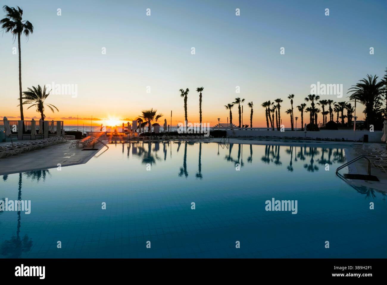 Chypre, Paphos, plage de Paphos avec des palmiers au coucher du soleil Banque D'Images