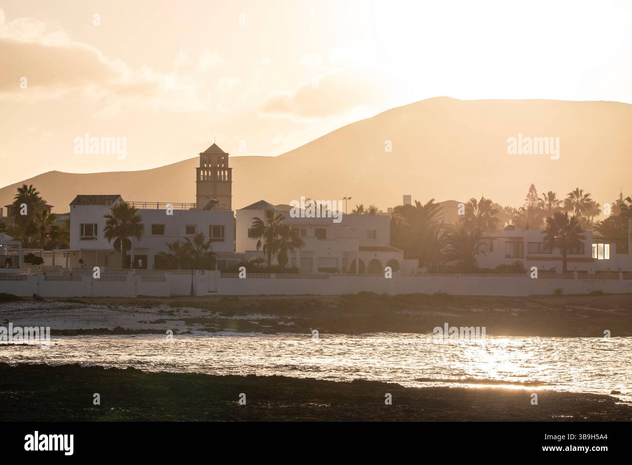 Coucher de soleil à Playa Vista Lobos, dans une longue exposition au bord de la mer, plage de lave avec vue sur la ville de Corralejo, Fuerteventura, îles Canaries, Espagne Banque D'Images