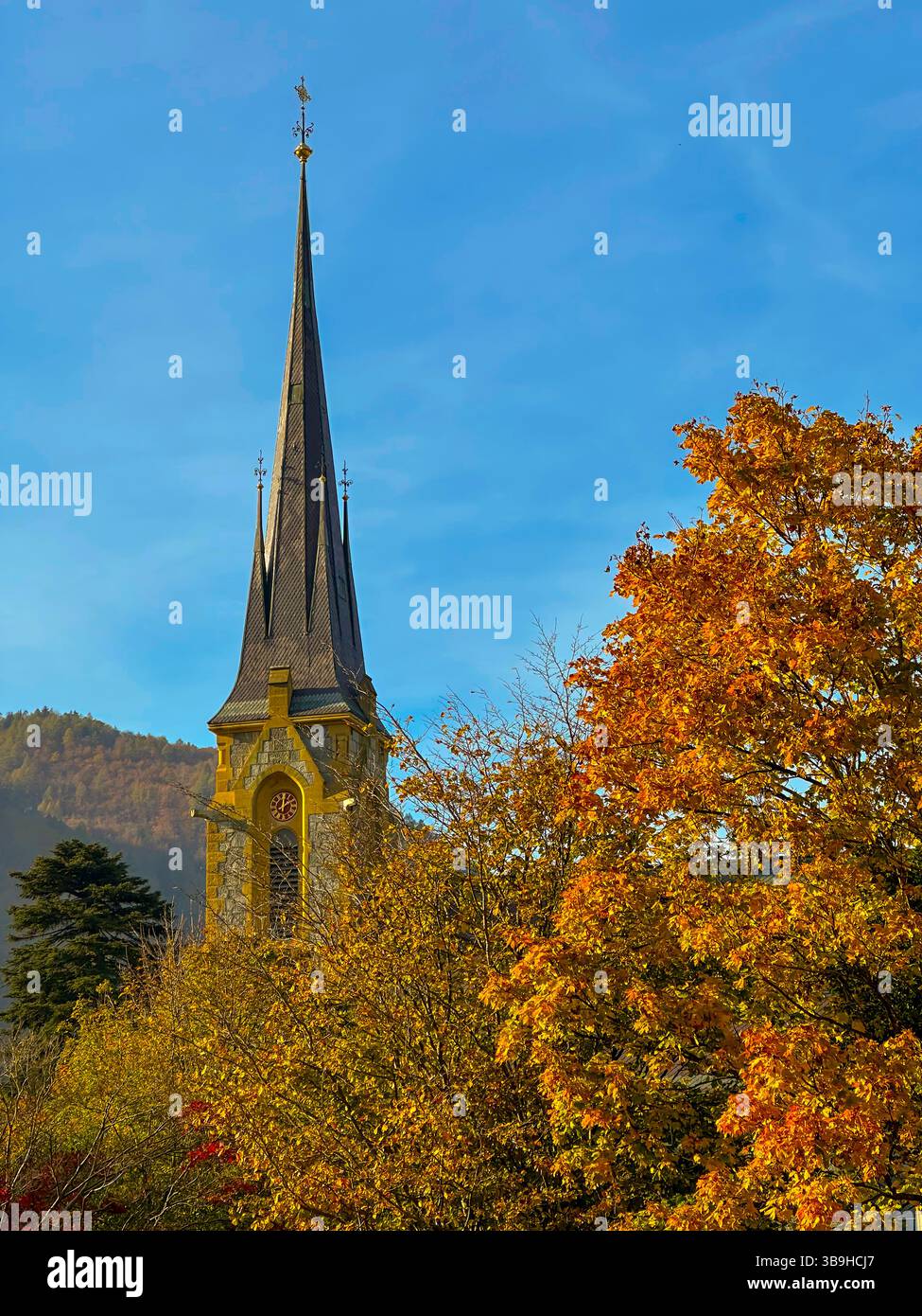 Tour de l'église et bel arbre d'automne et montagne avec ciel bleu dans un jour ensoleillé à Bad Ragaz, St Gall, Suisse. Banque D'Images