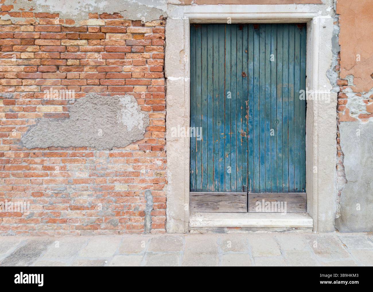 Vieille porte en bois bleu dans le mur de briques Banque D'Images