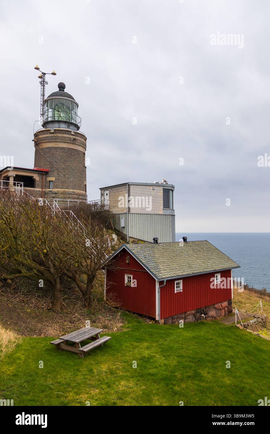 Vieux phare debout sur une falaise rocheuse au bord de la mer à Kullen, Suède. Jour de printemps couvert par la côte. Banque D'Images