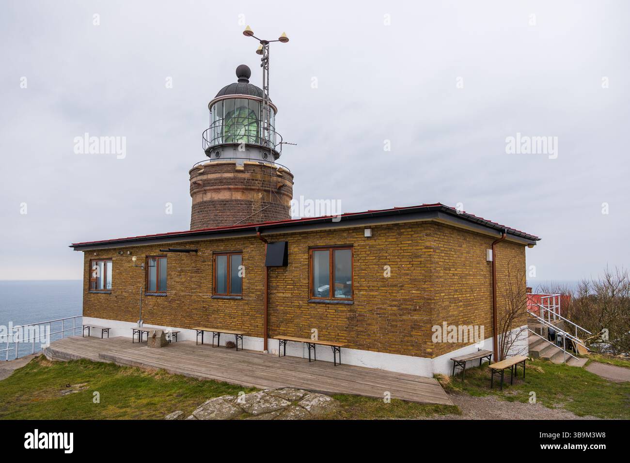 Vieux phare debout sur une falaise rocheuse au bord de la mer à Kullen, Suède. Jour de printemps couvert par la côte. Banque D'Images