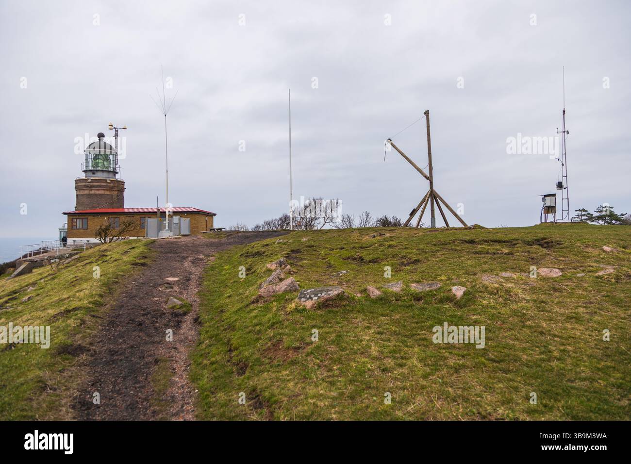 Vieux phare debout sur une falaise rocheuse au bord de la mer à Kullen, Suède. Jour de printemps couvert par la côte. Banque D'Images