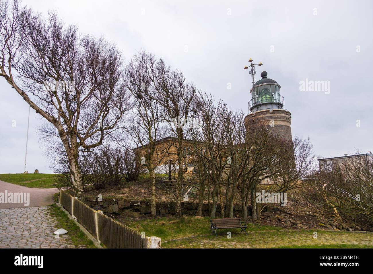 Vieux phare debout sur une falaise rocheuse au bord de la mer à Kullen, Suède. Jour de printemps couvert par la côte. Banque D'Images