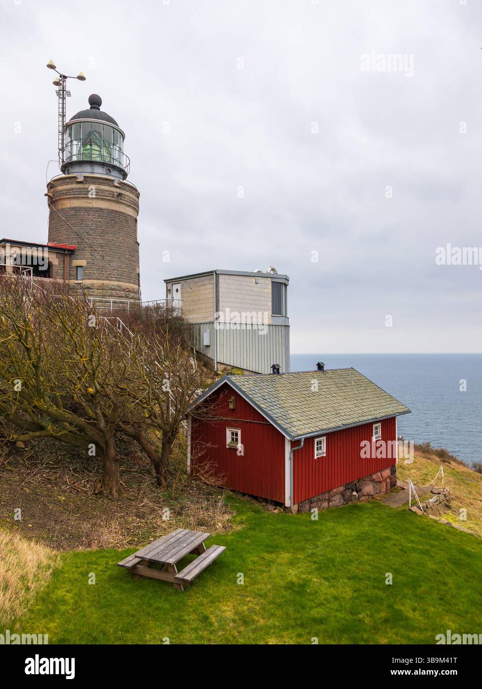 Vieux phare debout sur une falaise rocheuse au bord de la mer à Kullen, Suède. Jour de printemps couvert par la côte. Banque D'Images