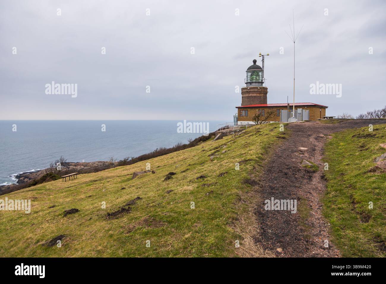 Vieux phare debout sur une falaise rocheuse au bord de la mer à Kullen, Suède. Jour de printemps couvert par la côte. Banque D'Images